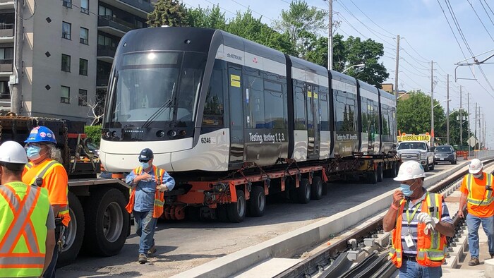 Des travailleurs devant un train léger.