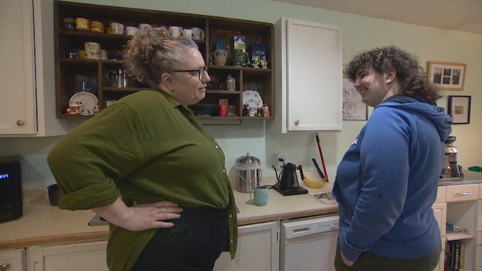 A woman and her young adult child are chatting in a kitchen.