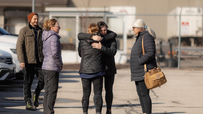 Des employés de Diageo à Amherstburg se serrent dans leur bras dans le stationnement de l'usine à la sortie de leur dernier quart de travail le mercredi 25 février 2026.