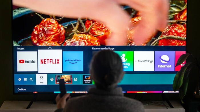 Une personne devant un écran avec différents choix de diffusion télévisuelle.