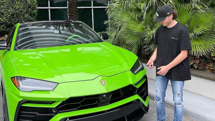 Aiden Pleterski se tient debout à côté d’une voiture verte de marque Lamborghini et de palmiers à Miami, en Floride.
