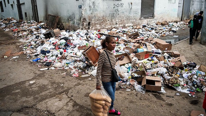 Une femme marche dans une rue jonchée d'ordures.