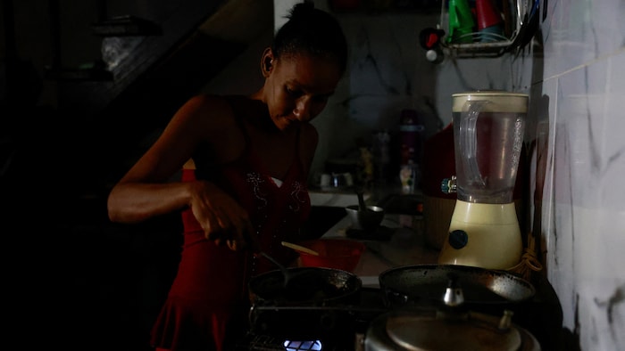 Une femme fait la cuisine dans la pénombre.