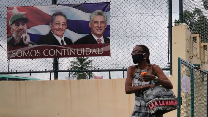 A woman passes by a poster displaying images of late Cuban President Fidel Castro, Cuba's First Secretary of the Communist Party and former President Raul Castro and Cuba's President Miguel Diaz Canel in Havana, Cuba, on April 12, 2021.