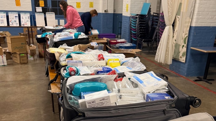 Des valises remplies de matériels médicaux sont ouvertes et alignées sur des tables. 