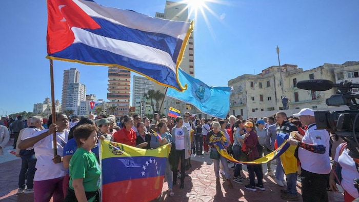 Des Cubains brandissent les drapeaux nationaux vénézuélien et cubain lors d'un rassemblement.