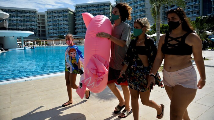 Cuatro personas caminan junto a la piscina de un complejo hotelero.