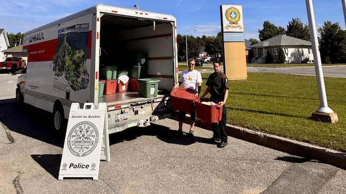 Deux personnes derrière un camion rempli de biens.