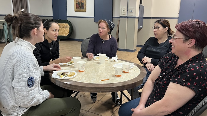 Cinq femmes sont assises autour d'une table et discute.