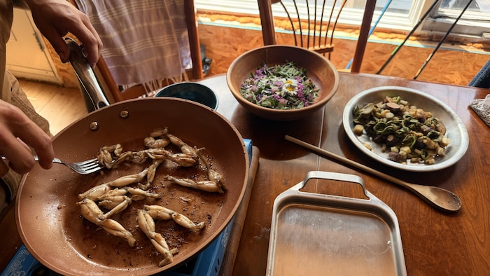Une poêle avec des cuisses de grenouilles.
