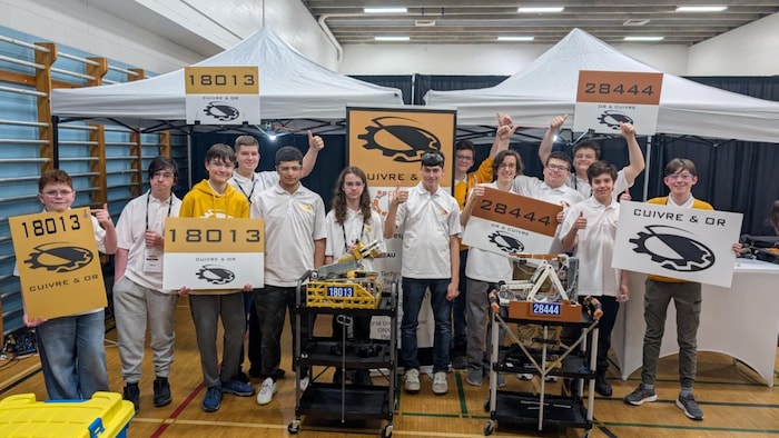 Des jeunes posent avec des affiches et des robots