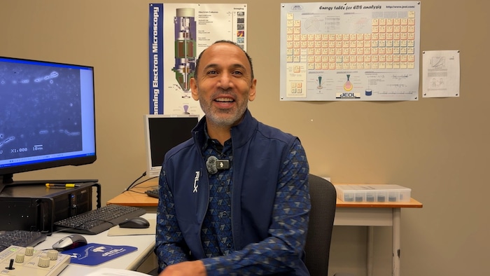 Un homme souriant assis sur une chaise dans un bureau.