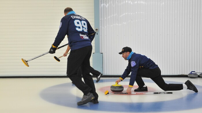 Des joueurs de curling s'apprêtent à lancer une pierre.