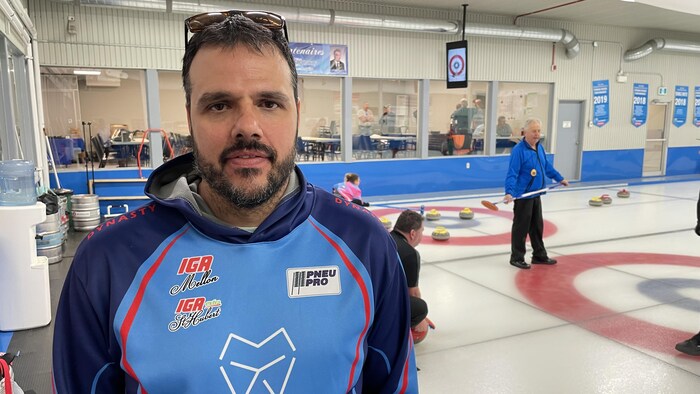 Un homme devant une glace de curling.