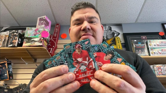 Curtis Howson, du magasin winnipégois First Row Collectibles, tient les premières cartes de la série First Peoples Rookie représentant d'anciens joueurs autochtones de la LNH en janvier 2023.