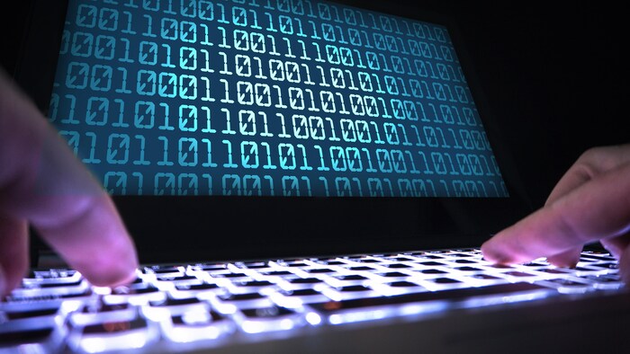 Des mains tapent sur les touches du clavier d'un ordinateur portable.
