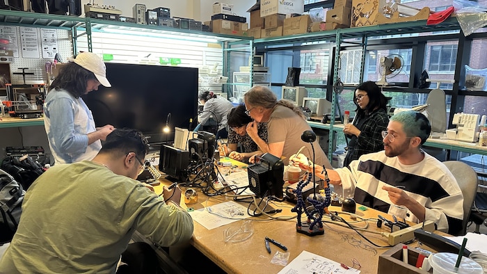 Un groupe de personnes travaillent sur des composants technologiques sur un établi dans un atelier.