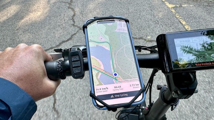 Un téléphone fixé au guidon d'un vélo affiche l'application «Cycling Guide» pendant un trajet sur une piste cyclable.