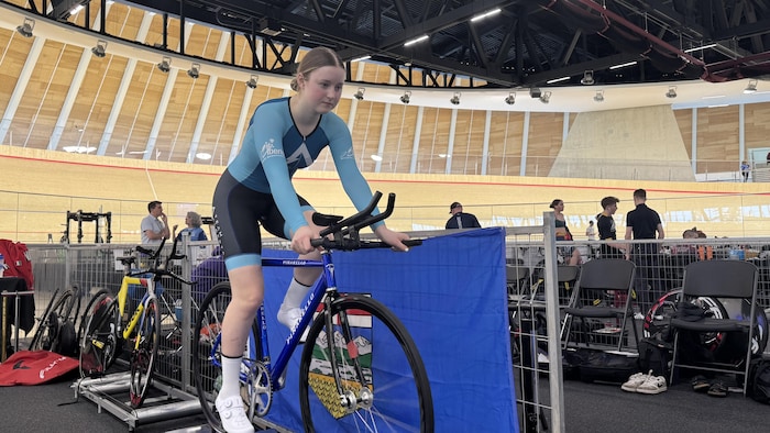 Une jeune cycliste pédale sur un vélo stationnaire.