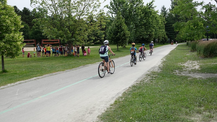 Quatre jeunes cyclistes circulent à vélo sur la piste cyclable du parc Lucien-Blanchard.