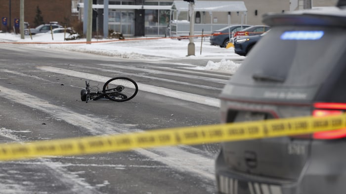 Un vélo sur la chaussée et une voiture de police.