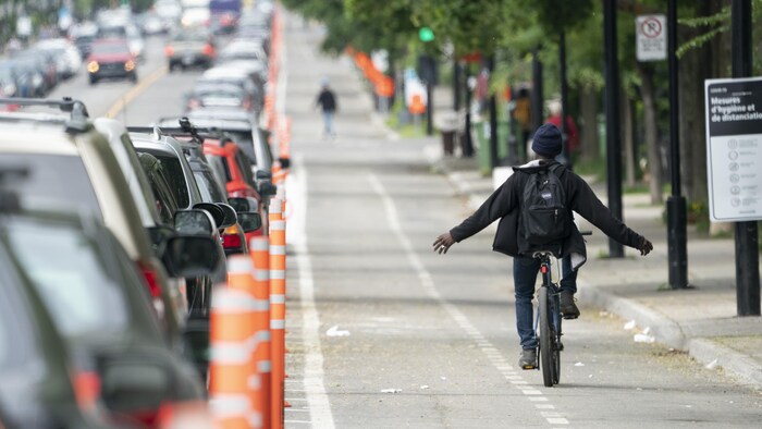 Un cycliste roule sans tenir son guidon dans les voies cyclables de l'avenue Christophe-Colomb.