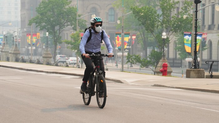 Un cycliste porte un masque dans une rue d'Ottawa.