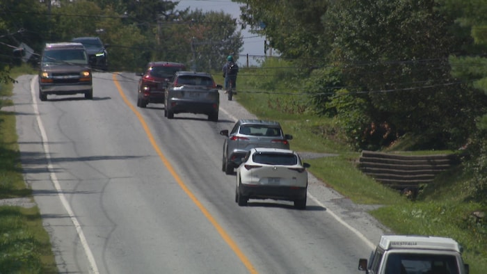 Des voitures à proximité d'un cycliste circulant sur la rue College.