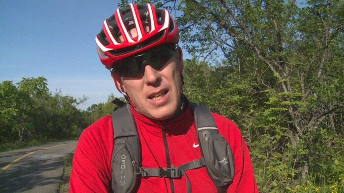 Le cycliste Martin Tellier répond aux questions d'un journaliste sur le sentier des voyageurs.
