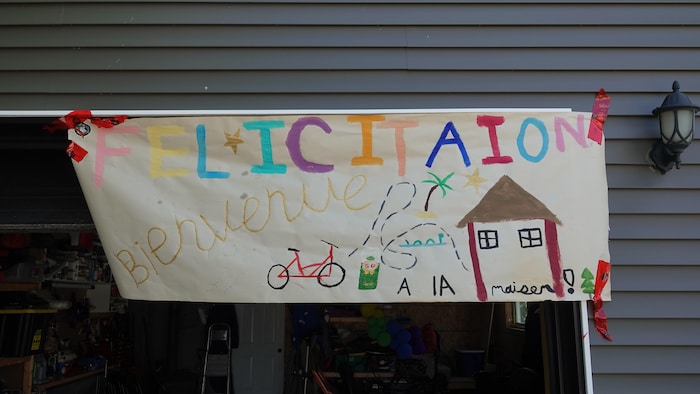 Une banderole peinte à la main où on peut lire le mot Félicitations et Bienvenue à la maison.