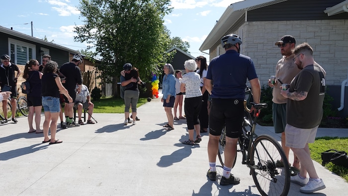 Un groupe de personnes discute autour de quelques cyclistes et certaines personnes s'étreignent.
