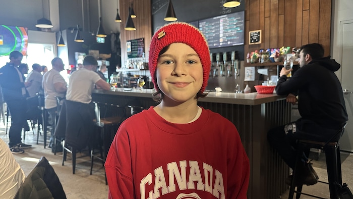 Un jeune garçon souriant dans un bar. 