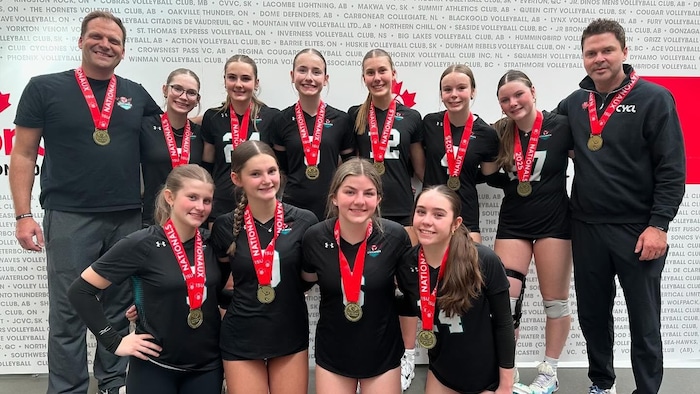 Une équipe de volleyball pose, médaille au cou.