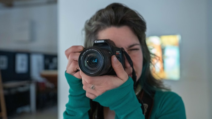 Une femme tenant un appareil photo devant son visage.