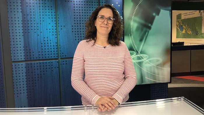 Une femme souriante sur un plateau de télévision.