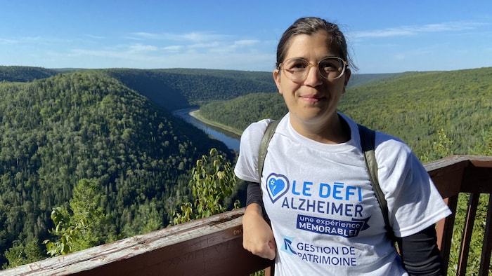Cynthia Dufour se trouve au Belvédère Saint-Alexis, on peut voir une rivière et des montagnes derrière elle.