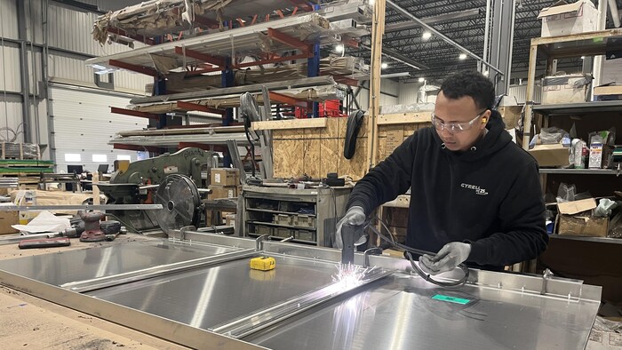 Un employé de Cyrell Amp effectue une opération sur un panneau en aluminium.