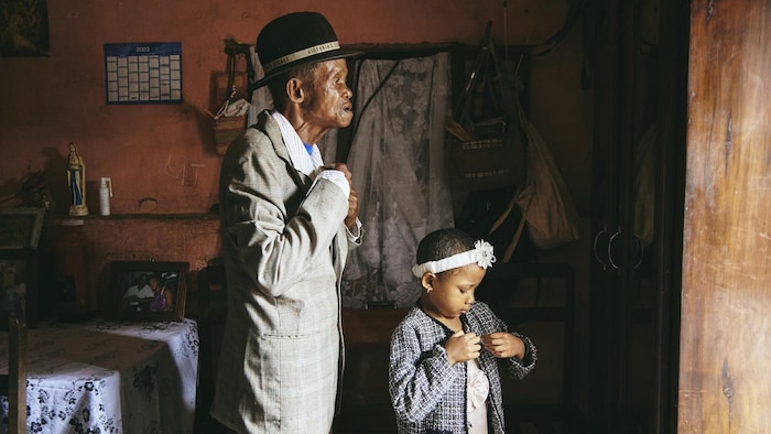 Un vieil homme et une petite fille s'habillent dans une maison rustique. 