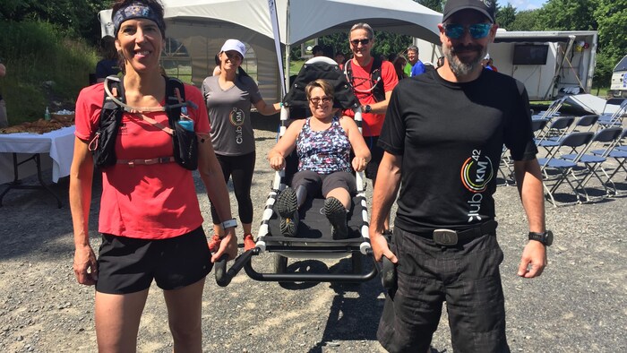 Des bénévoles apportent une personne à mobilité réduite dans un sentier de la montagne. 
