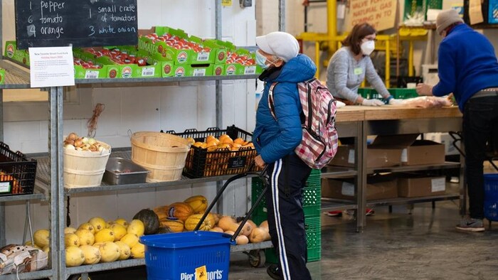 Une femme regarde l'étalage de légumes d'une banque alimentaire.