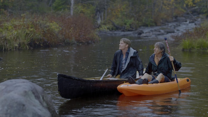 Deux hommes font du canot et du kayak sous la pluie.