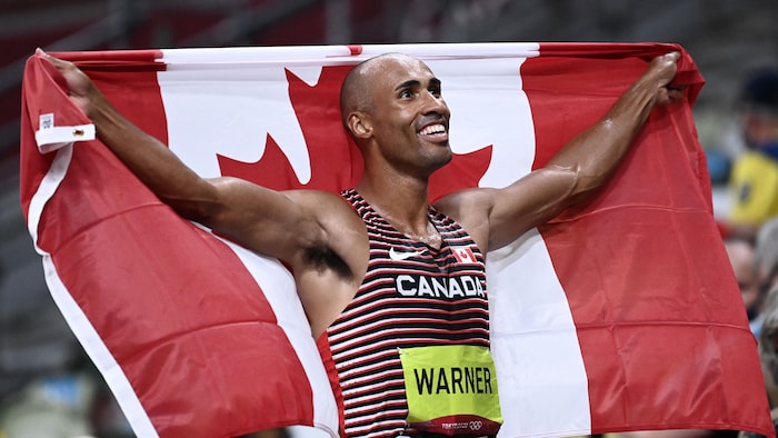 Un homme affiche un large sourire en arborant le drapeau canadien.