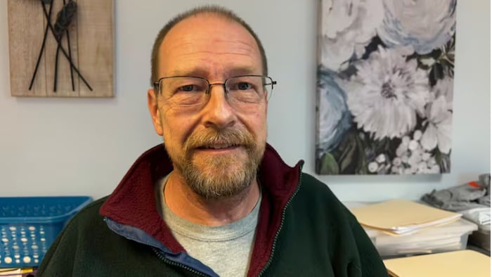 Portrait de Damon Lieurance devant un mur orné de tableaux de fleurs.