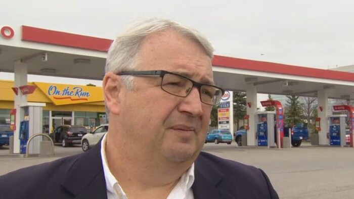 Gros plan sur Dan McTeague devant une station d'essence.