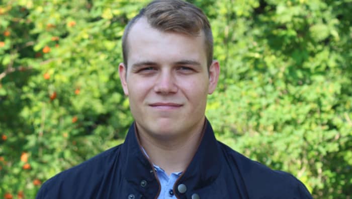 Portrait épaule du député Dane Lloyd devant un buisson de verdure