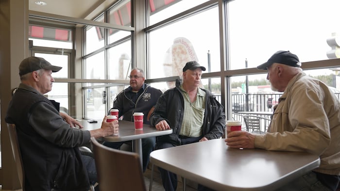 Quatre personnes discutent assises dans un café.