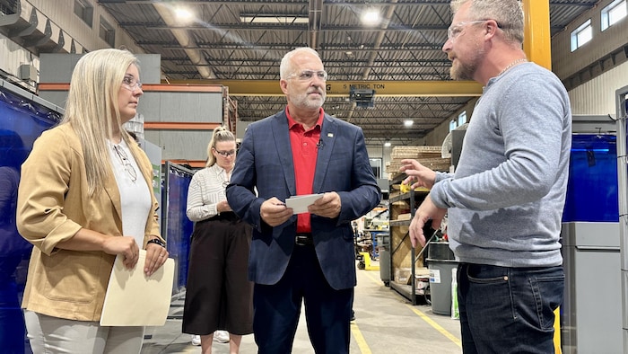 Daniel Gobeil parle avec deux personnes dans une usine d’aluminium.