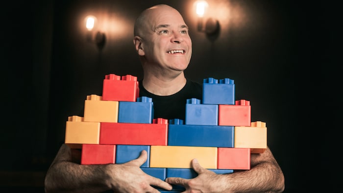 L'humoriste pose avec des blocs Lego géants dans les bras. 