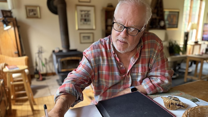 Un homme esquisse un dessin sur une table à laquelle il est assis.