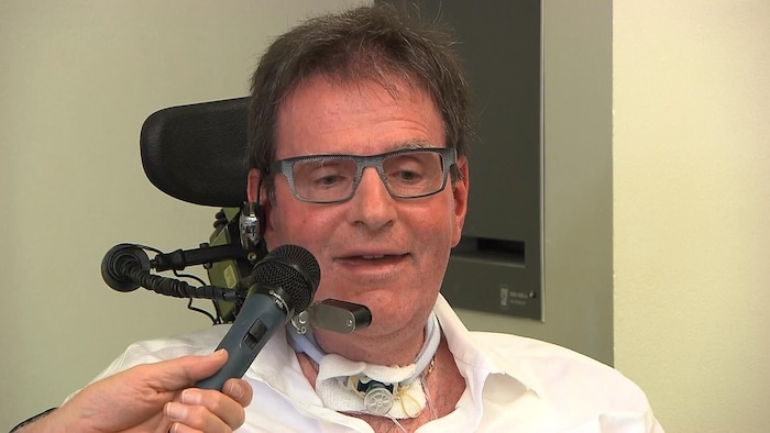 Un homme en fauteuil roulant parle au micro.